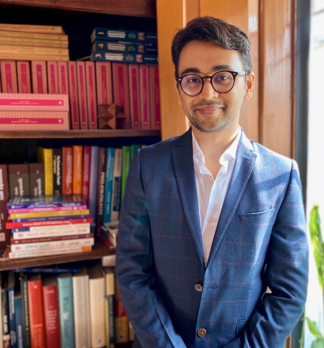 person with glasses in front of bookcase