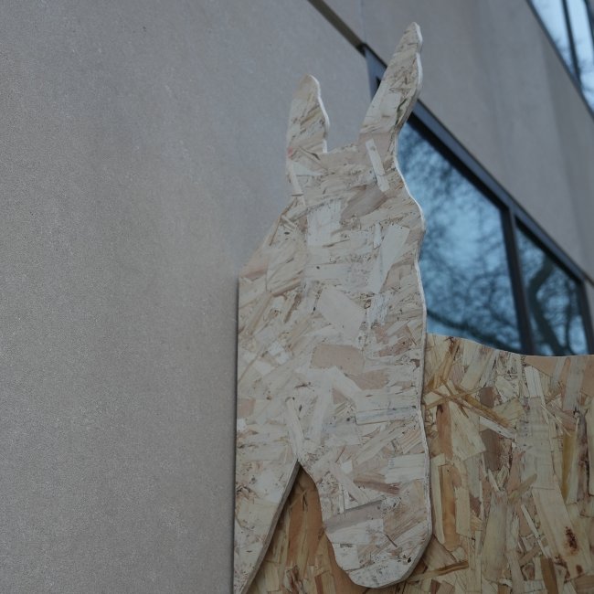 Installation view of a life-size silhouette of a horse made from plywood