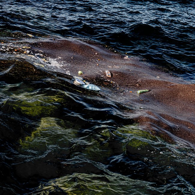 Debris and silt floating in a deep blue-green, waving body of water